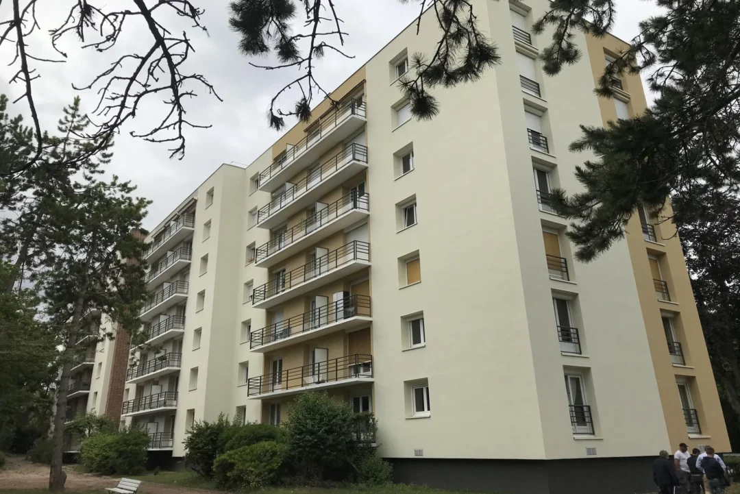 Immeuble résidentiel moderne avec balcons, arbres devant.