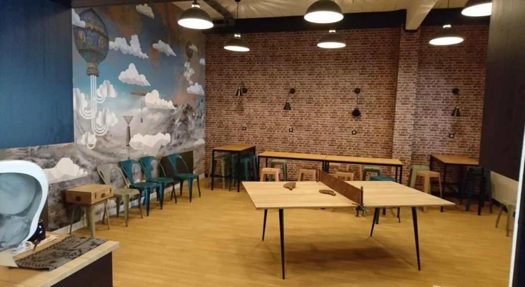 Salle avec table de ping-pong et mur brique.
