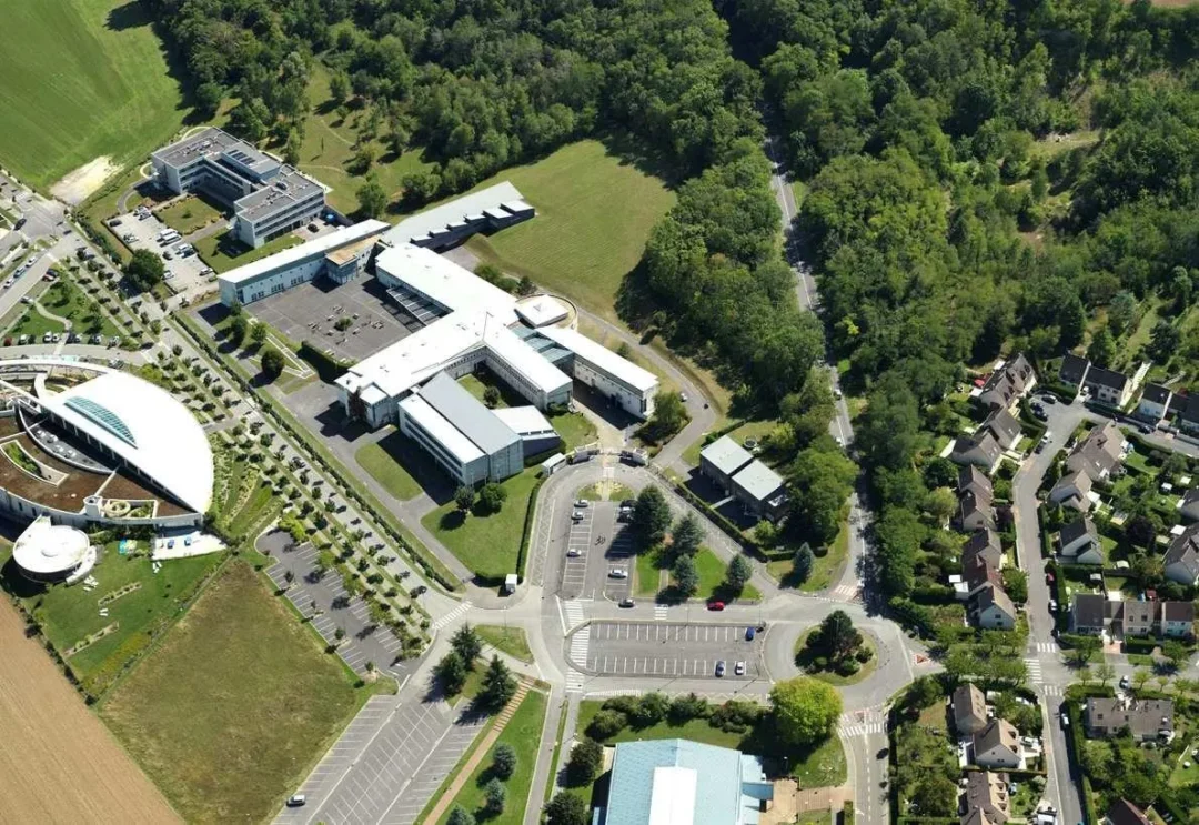 Vue aérienne d'un complexe universitaire entouré de verdure.