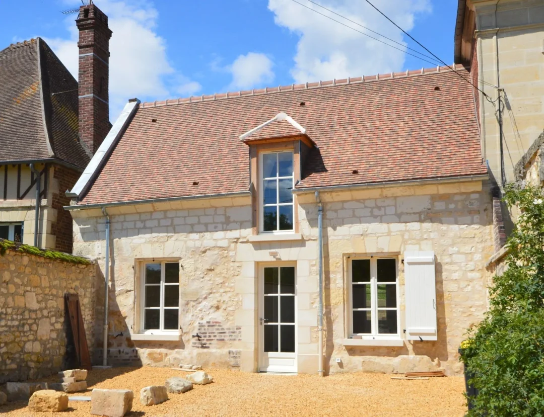 Maison en pierre avec toit en tuiles rouges.