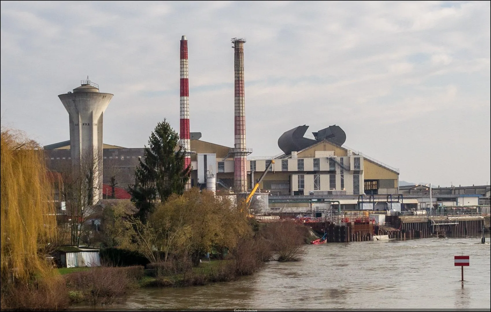 Centrale avec cheminées et rivière au premier plan.
